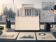 A calm editorial illustration of economic charts, a calendar and a central-bank building on a desk