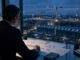An analyst studies a financial statement beside a vast illuminated data-centre construction site, representing the link between technology investment and cash flow