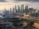 European city economy combining port logistics, rail infrastructure, construction, offices and manufacturing at sunrise